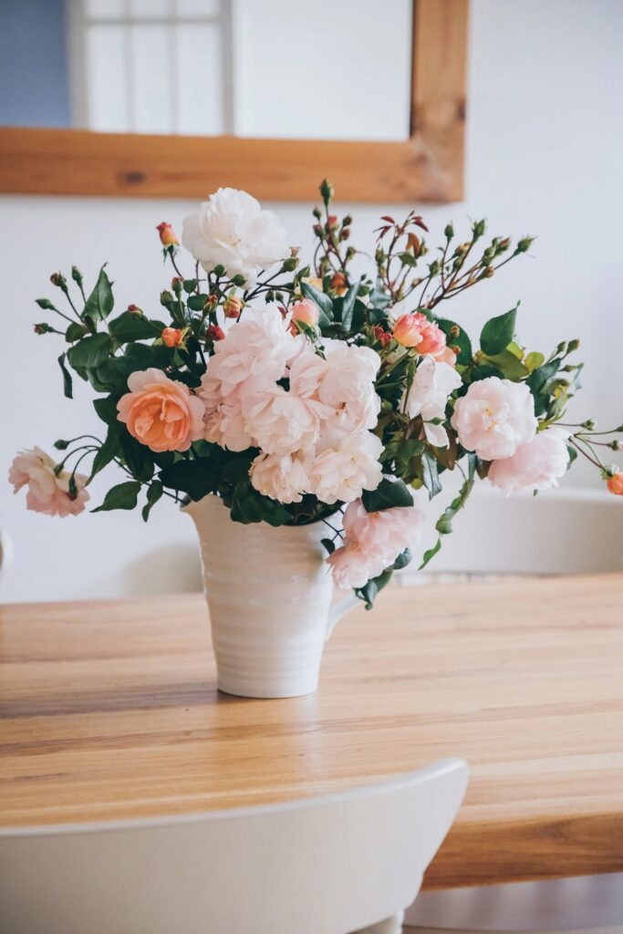 Freshly cut pale pink English rambling rose in white vase